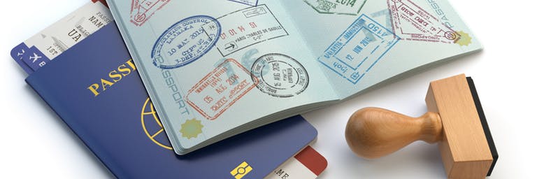 close up shot of a blue passport with boarding pass and another one open with multiple stamps