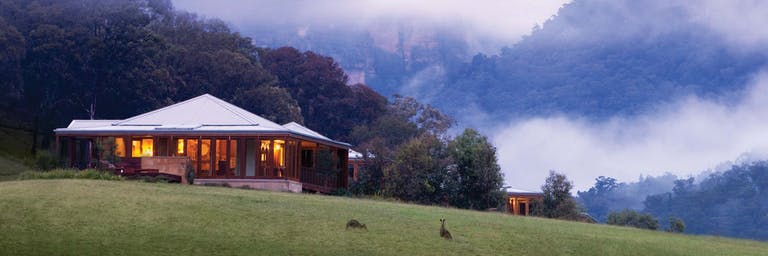 view of the Emirates One&Only resort and two kangaroos in hazy Wolgan Valley in Australia