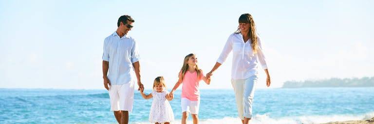 happy family holding hands walking on a beach together