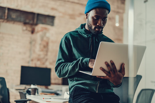 Waist up of calm man sitting with laptop in his hands