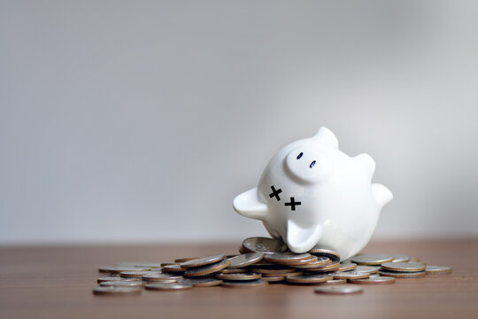 The dead piggy bank lies upside down on coins, Economic crisis, Decrease, layoff, job fired, pay cuts, low cost, collection