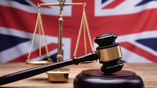 Gavel and weighing scales sit on table in front of UK flag