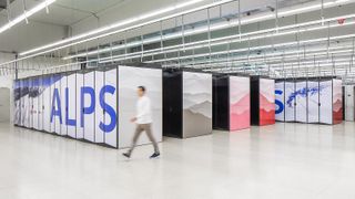 A photo of Alps supercomputer infrastructure in Lugano, Switzerland. A worker is blurrily walking in front of HPE supercomputer stacks which bear the words 