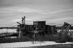 A black and white photo of a deserted gold dredge outside Nome, Alaska. This large piece of equipment, like many other dredges in the area, was operated for a few years and then abandoned in place.