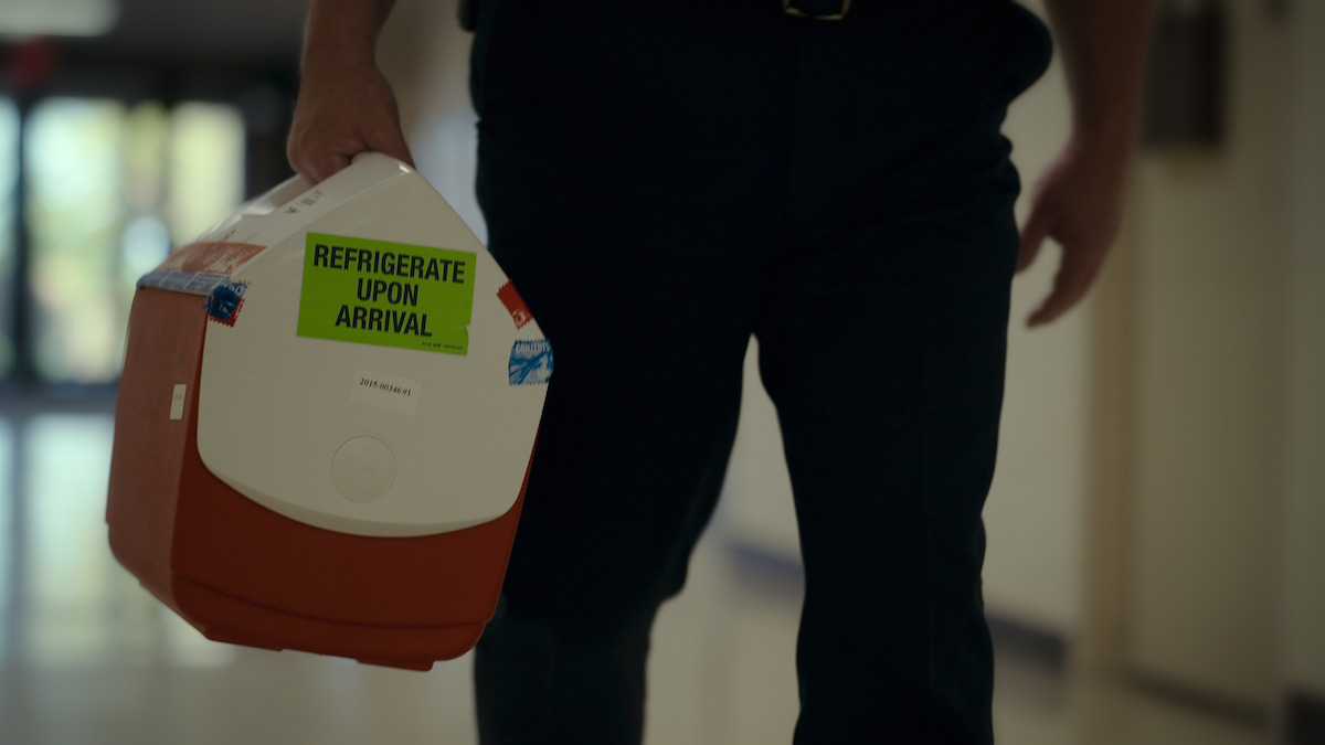 A cooler with evidence being carried in a scene from ‘Unsolved Mysteries’.