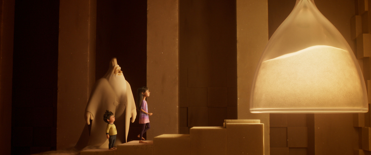 A large white-bearded man and a pair of children ascend a set of stairs towards a giant hourglass in a still from ‘In Your Dreams.’