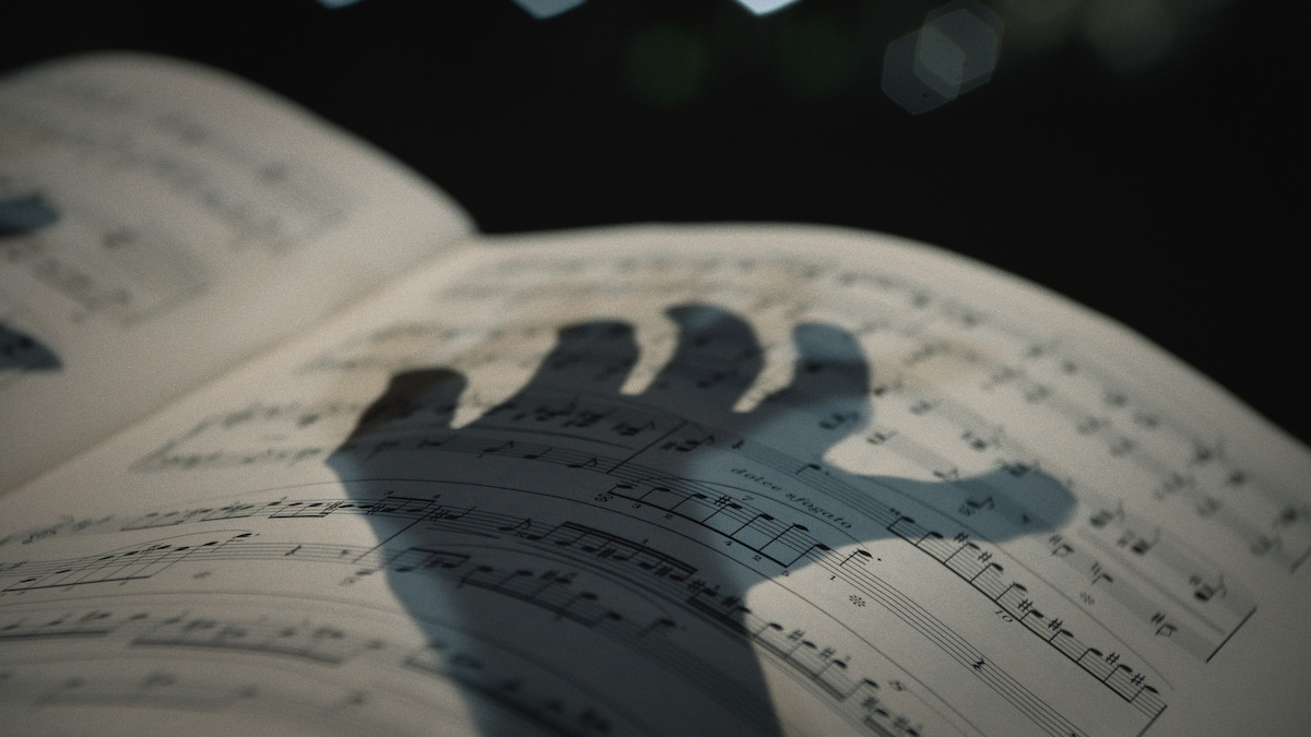 A shadow of a hand appears over sheet music in a scene from ‘Unsolved Mysteries’.