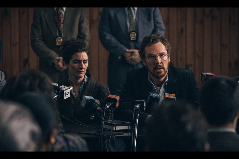 A close up of a seated man and woman at a press conference.