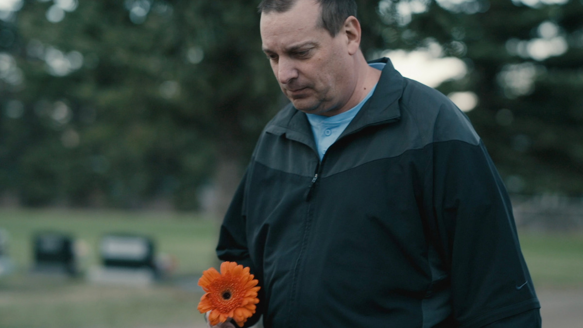 Amanda's brother Darrell Hogg holds a flower that he will place on her grave.