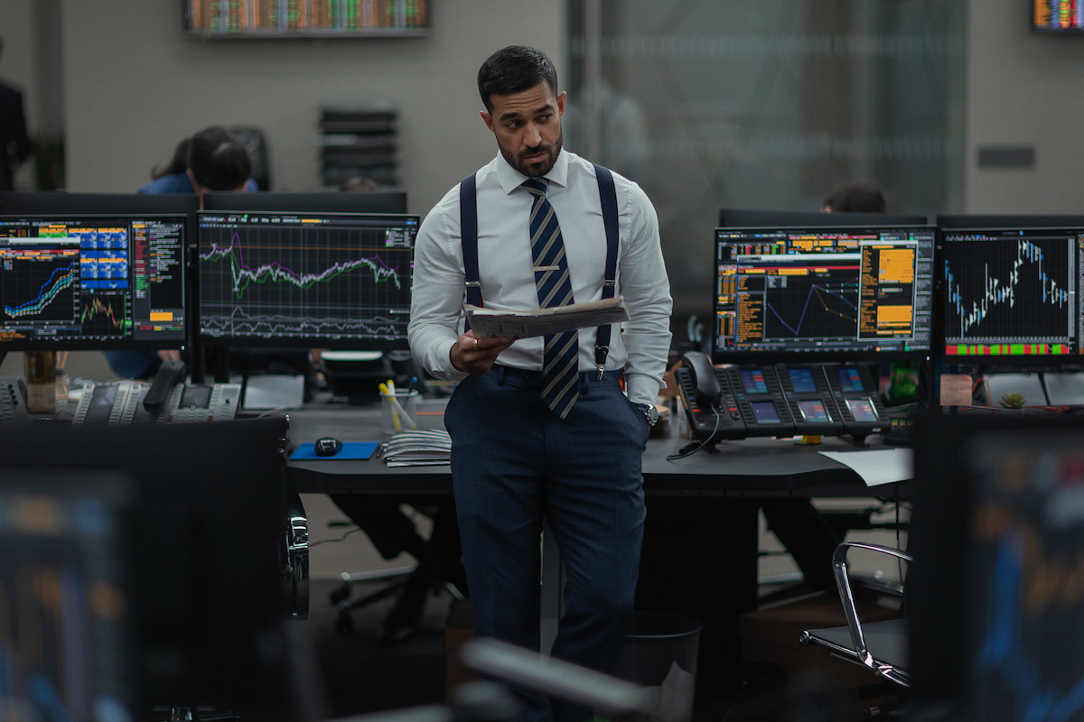 Sia Alipour as Arjun holds a paper while leaning against a desk.