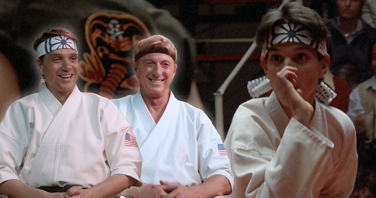 Ralph Macchio and William Zabka sit together in karate uniforms smiling looking at a young Ralph Macchio in 'The Karate Kid'