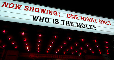 A marquee that reads 'NOW SHOWING; ONE NIGHT ONLY WHO IS THE MOLE?'