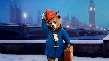 A bear wearing a blue coat tips his hat in front of Big Ben in London