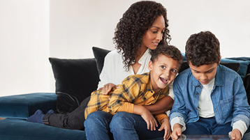 A mother and her two sons look at a tablet together