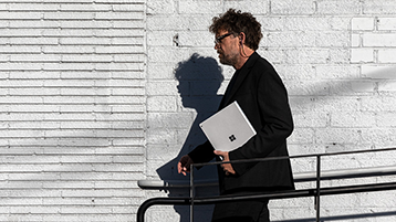 Un homme qui marche et tient un Surface Book