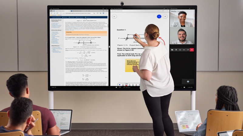 Skolotājs atrodas mācību priekšpusē ar tinti centrmezglā 85" ar gaiši pelēku Surface pildspalvu. Ekrānā ir redzama Edge Whiteboard un Teams. Priekšplānā vairākiem skolēnam ir Pro 7+ un viņi veic piezīmes programmā One Note.