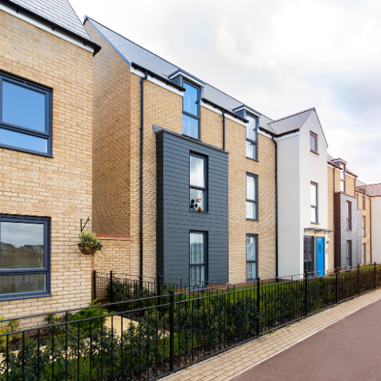 Modern flats along a red pavement with a cloudy sky in the background