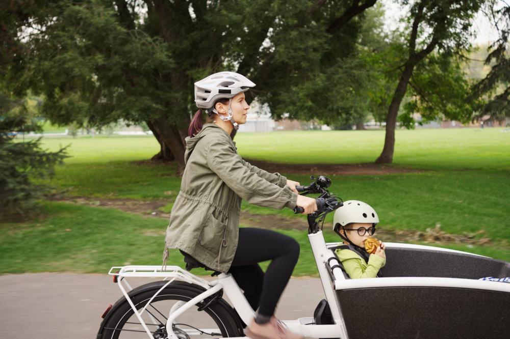 woman cycling a cargo bike with a child