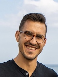 Ben smiling with a waterfront in the background.