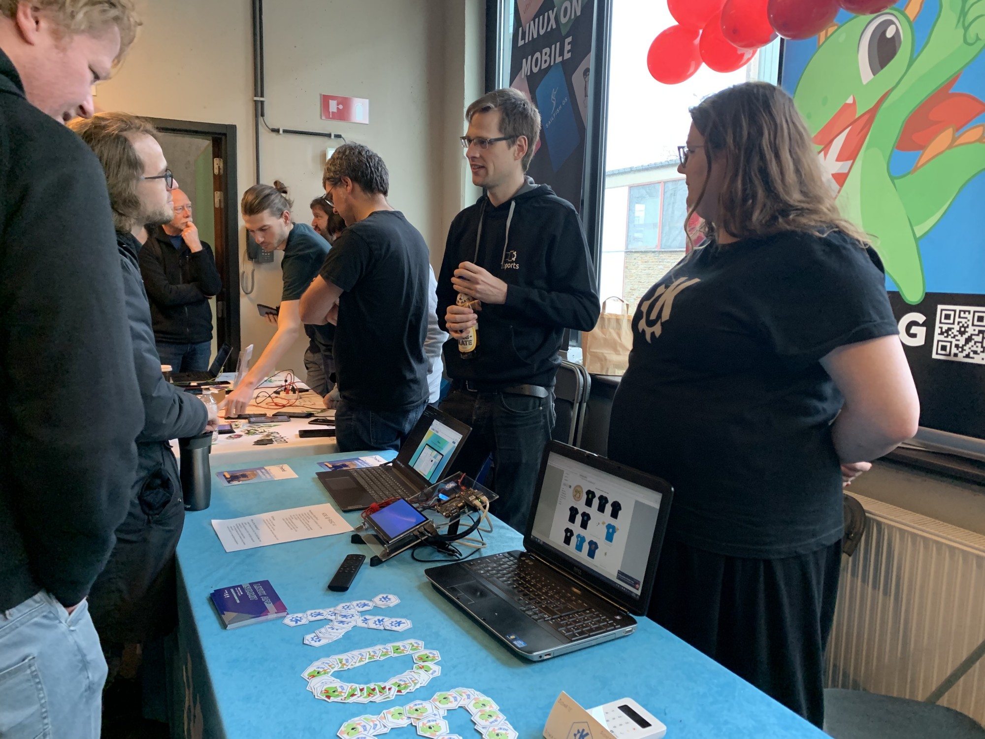 Photos showing the booth with devices and merch and attendees browsing.