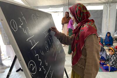 Woman wearing a headscarf and writing on a blackboard