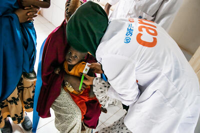 A healthcare worker from CARE, supported by SHF funding, provides medical care to a young child at Tawakal Health Center in Galkayo, Somalia, amidst the severe drought crisis of July 2023.