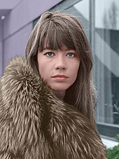 Photographie d'une femme aux yeux bleus, ayant une frange et un manteau de fourrure.