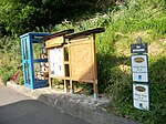 Cabine téléphonique transformée en bibliothèque de livre à échanger. Panneau d'information de la mairie et récompenses du Grand prix des années 2013 et 2014 du Village Fleuri de la Haute-Garonne