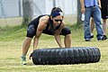 Woman lifting a 200 pound tyre – bent knees essential to avoid back strain.