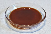 Brown, slightly translucent liquid in a flat, transparent glass dish.