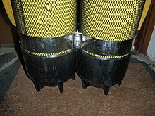 The lower part of a twin steel set showing a stainless steel tank band just above the black plastic cylinder boots. The boots and tank band have been fitted over close fitting small mesh netting covers intended to protect the paintwork and facilitate rinsing and drying of the surface under the boots.