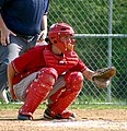 A baseball catcher in squatting position, prepares to receive a pitch.