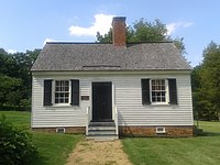 Small cottage with white walls, black door, and brick chimney