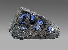 Bright blue scorodite crystals on brown-black beudantite, 8 x 5 x 3 cm.