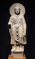 A statue of a standing man wearing a cloak