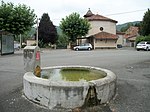 Place centrale du village avec un abreuvoir et l'église Saint-Jean-Baptiste en arrière plan