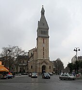 Église en pierres beiges et au clocher gris.