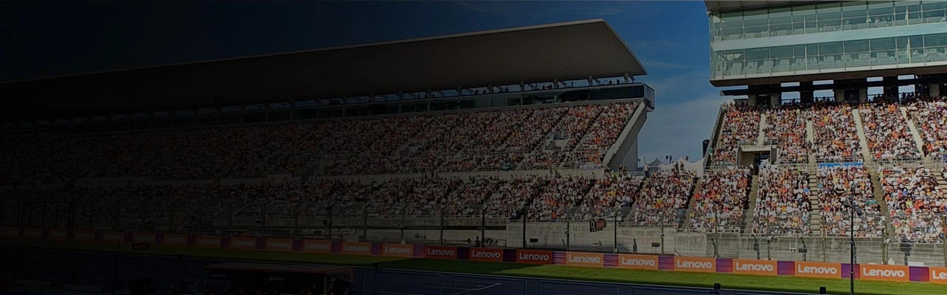 View of the inside of a racetrack with a large number of people in the stand watching 