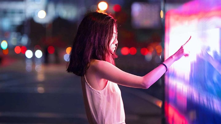 A woman touching an interactive map on a street