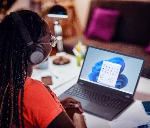 A high school student sits at a desk, working on her laptop.