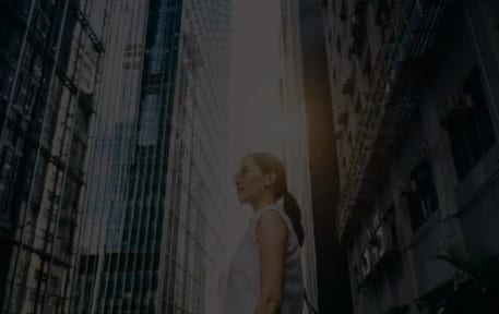 a woman standing under multiple big building