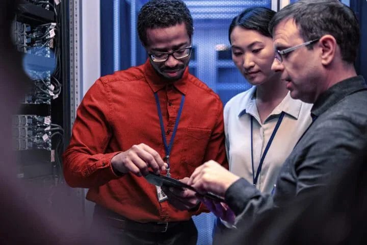 Three IT professionals collaborating over a tablet