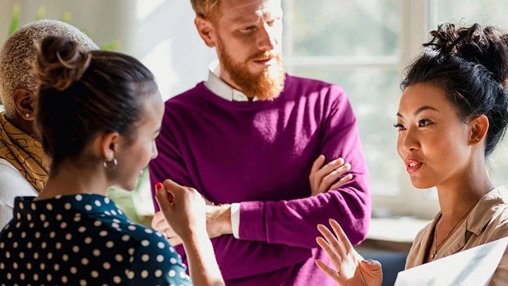 A group of employees listening to a woman speak