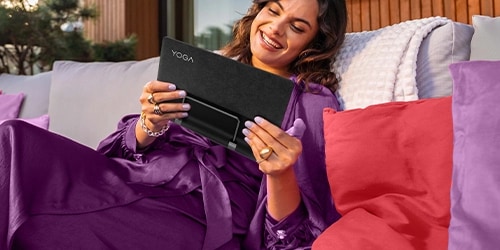 Woman holding a Lenovo Tablet while smiling and sitting relaxed