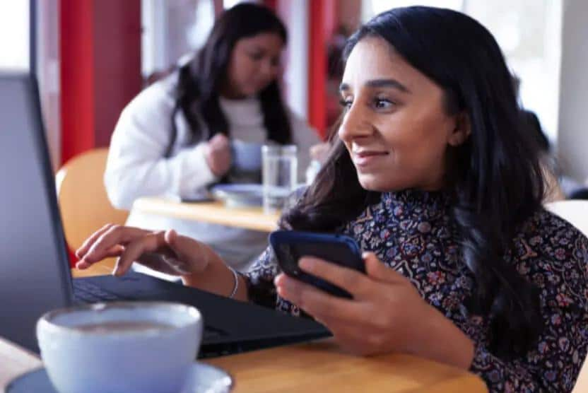 Woman sitting at table using Lenovo laptop.