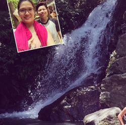 Attractive girl takes selfie near a waterfall while on tour