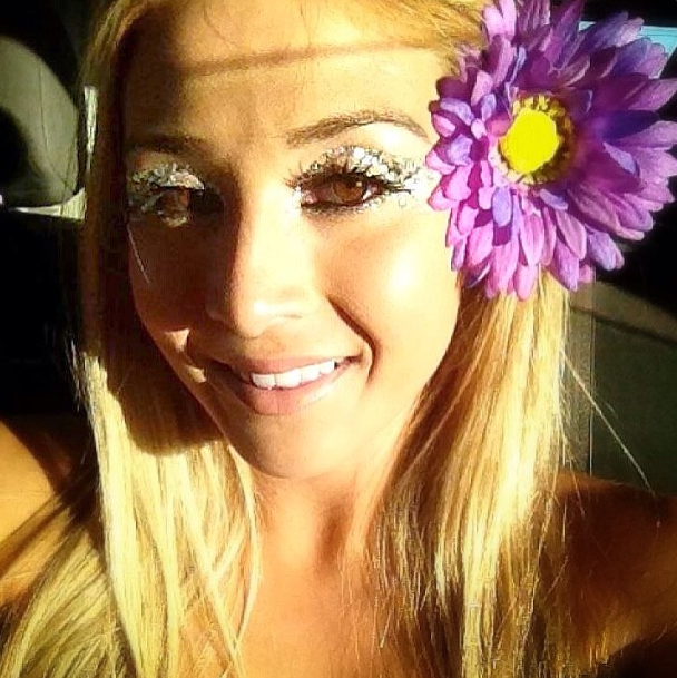 A charming blonde girl with a flower in her hair smiles on a beach