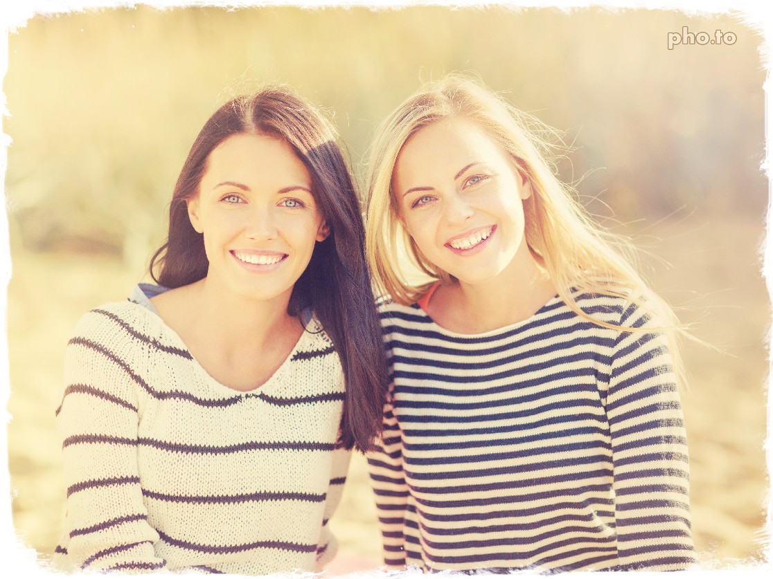 A portrait photo of two beautiful girls edited with a color filter to add warm and golden tints