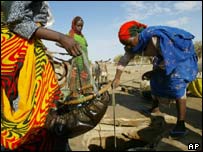 Refugees from Darfur pump water across the border in Chad