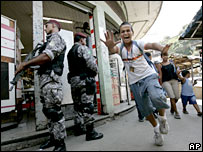 A boy runs past police officers guarding the streets of the Complexo de Alemao slum in Rio de Janeiro, 6 March 2008 